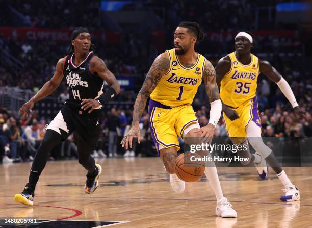 Angelo Russell of the Los Angeles Lakers dribbles away from Terance Mann of the LA Clippers as Wenyen Gabriel follows during the first half at...