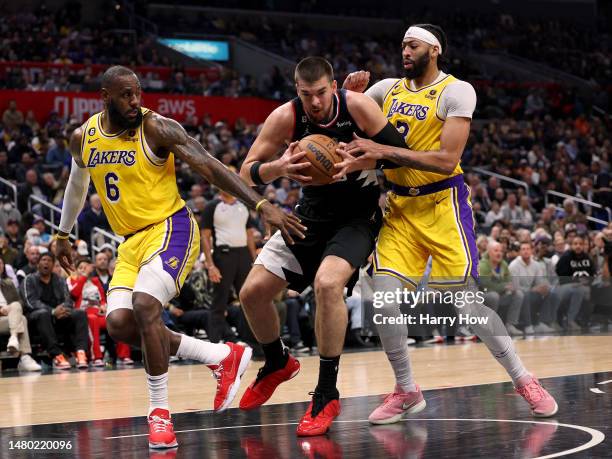 Ivica Zubac of the LA Clippers grabs a rebound between LeBron James and Anthony Davis of the Los Angeles Lakers during a 125-118 Clippers win at...