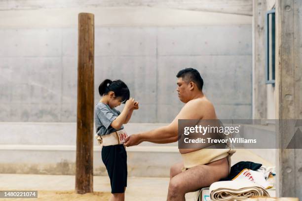 coach preparing a female student before sumo practice - martial arts stock pictures, royalty-free photos & images