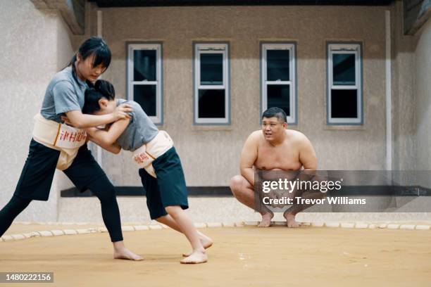 sumo coach supervising two elementary school-aged girls during a practice - female wrestling stock pictures, royalty-free photos & images