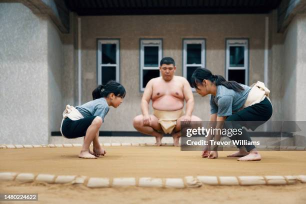 sumo coach supervising two elementary school-aged girls during a practice - female wrestling stock pictures, royalty-free photos & images