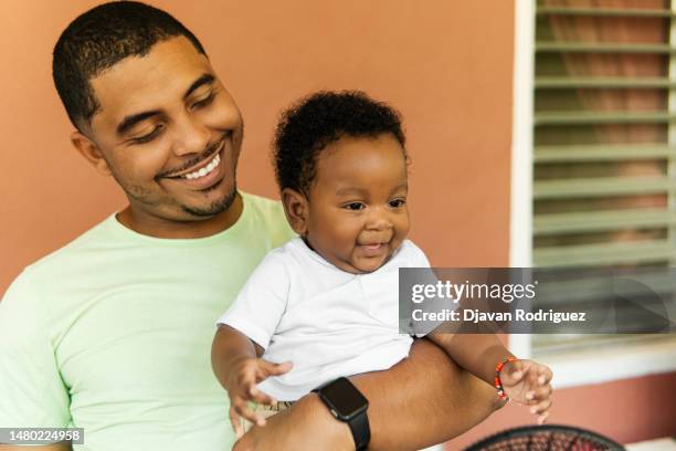 portrait of young adult african uncle man holding his nephew. - honduras people stock pictures, royalty-free photos & images