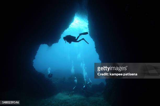 divers with cave silhouette scene, koh ha yai, krabi province, thailand. - deep hole stock pictures, royalty-free photos & images