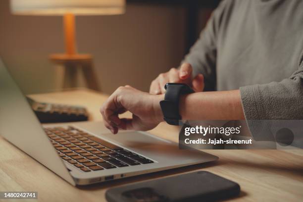 close-up shot of female's hand with smartwatch sitting at home office. - smart watch on wrist stock pictures, royalty-free photos & images