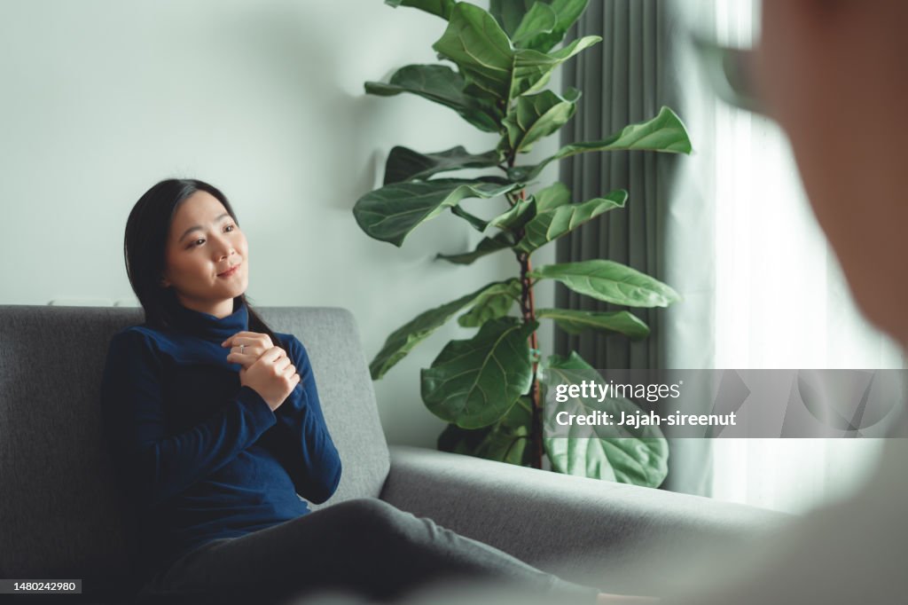 Asian woman talking with psychologist about problems after married sitting on sofa in counseling office.