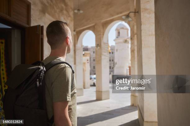tourist walking through narrow street - qatar mosque stock pictures, royalty-free photos & images