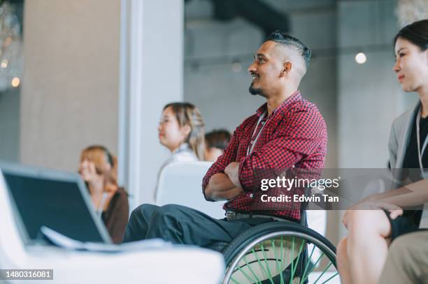 asian indian disable man in wheelchair listening to presenter's speech on stage in business conference meeting - lichamelijke beperking stockfoto's en -beelden