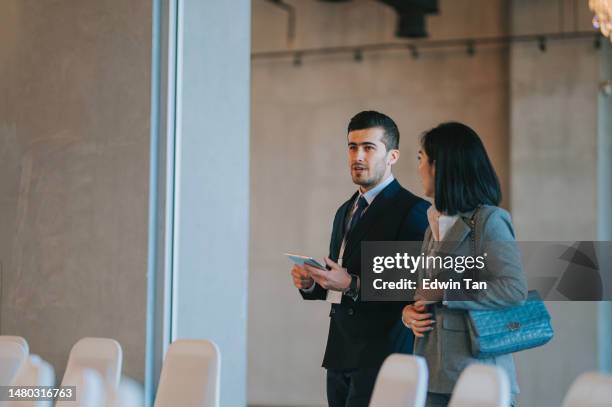 asian chinese businesswoman final check going  through programme details with banquet hall manager before the business conference seminar begin - banquet hall stockfoto's en -beelden