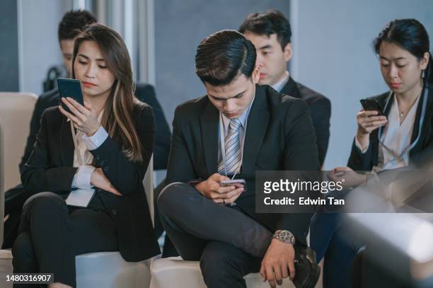 asian chinese seminar participants using smart phone text messaging while waiting in business conference room - bored audience stock pictures, royalty-free photos & images