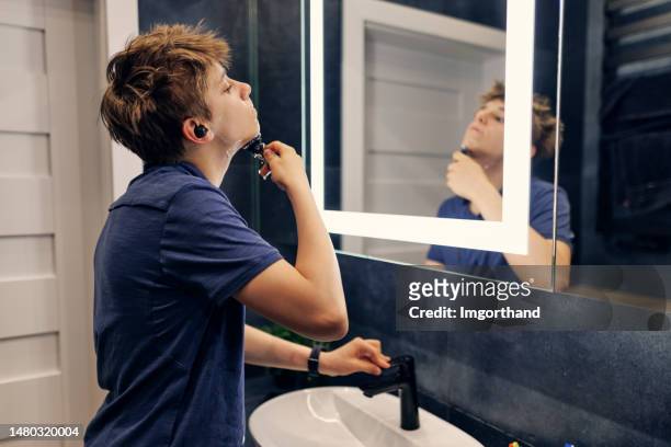 teenage boy is preparing to go out in a modern dark bathroom - teenage boy shave imagens e fotografias de stock