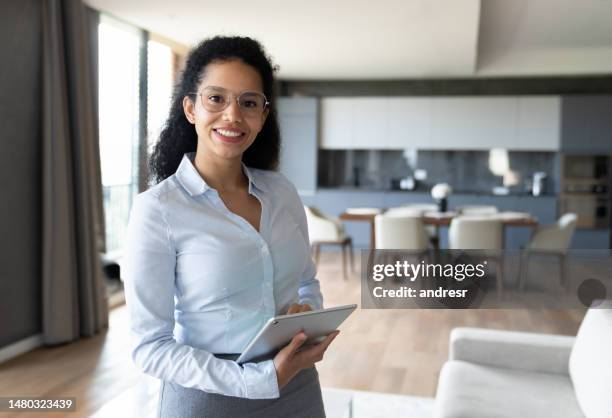 happy real estate agent using a tablet while showing a house - real estate developer stock pictures, royalty-free photos & images