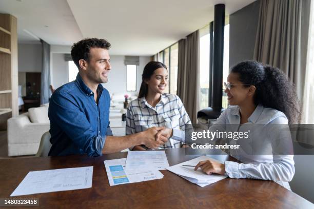 couple buying a house and closing a deal with the real estate agent - signing mortgage stock pictures, royalty-free photos & images