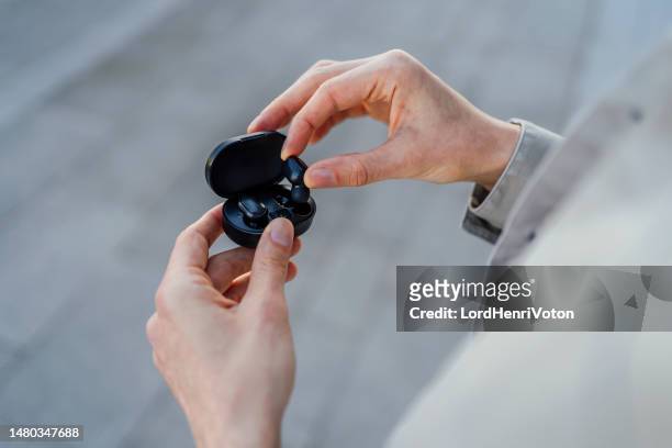 mann nimmt einen kabellosen ohrhörer aus der ladebox - in ear headphones stock-fotos und bilder