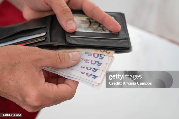 man's hands holding wallet and colombian pesos bills - colombian peso stock pictures, royalty-free photos & images