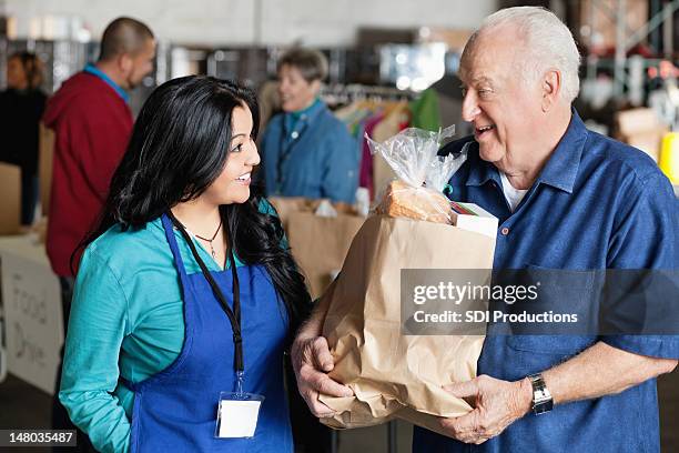 senior man talking to food donation volunteer - man offering bread stock pictures, royalty-free photos & images