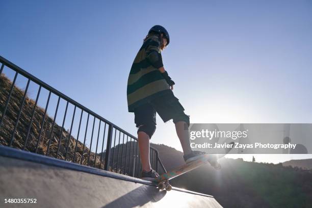 androgynous young girl skating on skateboard in the skate park - skate half pipe stock pictures, royalty-free photos & images