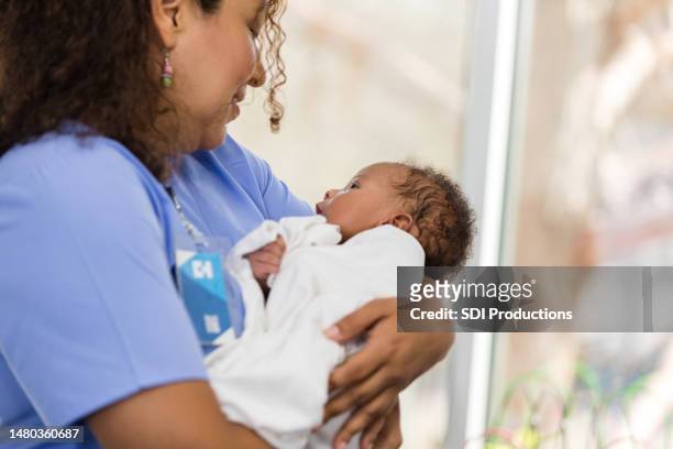 profesional médica femenina hace contacto visual con un bebé pequeño - compassionate eye fotografías e imágenes de stock