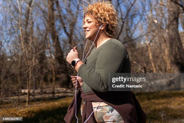 chubby woman with curly hair running - fat loss training stockfoto's en -beelden