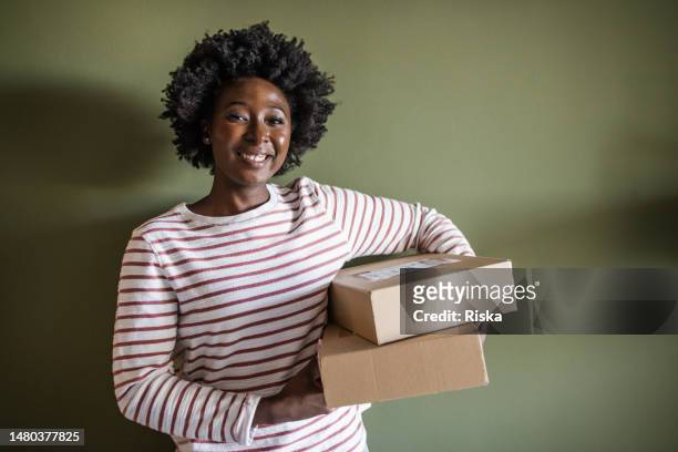 una mujer sonriente sostiene cajas de entrega - receiving fotografías e imágenes de stock