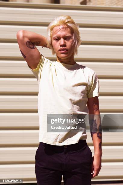 young gay man with yellow hair in front of a yellow background, wearing yellow t-shirt - t shirt stock pictures, royalty-free photos & images