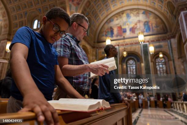 Kenneth Vestal and his son Aiden DeKaser, 10 pray as Cardinal Wilton Gregory, archbishop of Washington holds Holy Thursday mass at Cathedral of St....