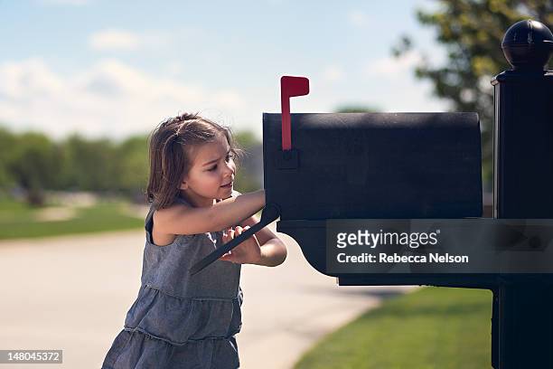 girl putting letter into mailbox - letter box stock pictures, royalty-free photos & images