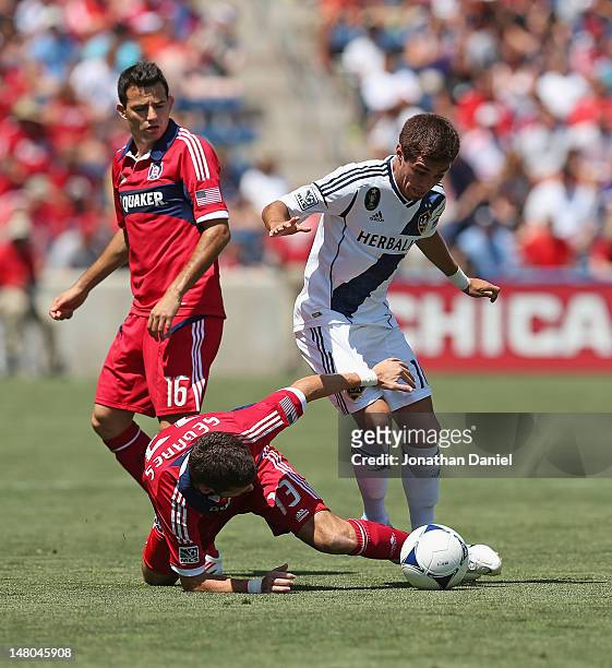 Gonzalo Segares of the Chicago Fire tries to kick the ball away after falling next to Hector Jimenez of the Los Angeles Galaxy as Marco Pappa watches...