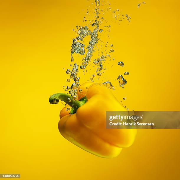 yellow pebber splashed into water - gelbe paprika stock-fotos und bilder