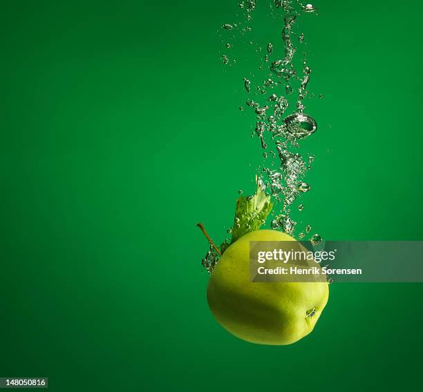 green apple splashed into water - apple water splashing stock pictures, royalty-free photos & images