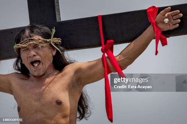 Penitent Ruben Enaje grimaces in pain as he is nailed to a cross during Good Friday crucifixions on April 07, 2023 in San Fernando, Pampanga,...