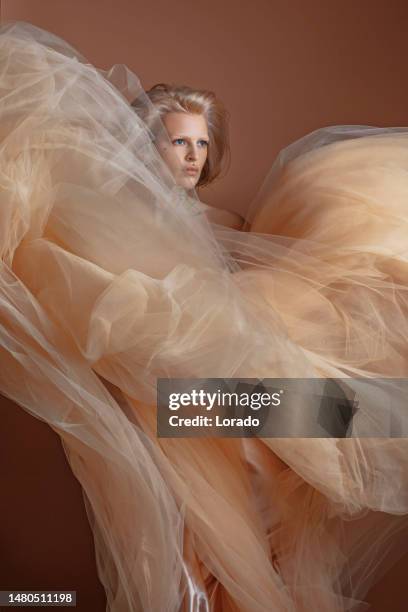 eine schöne blonde frau in einem cremefarbenen kleid - cremefarbiges kleid stock-fotos und bilder