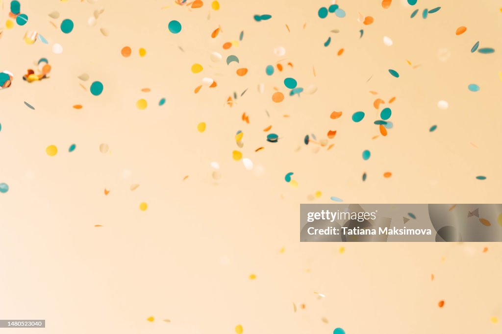 Festive background with flying confetti on peach color background, 3d effect.