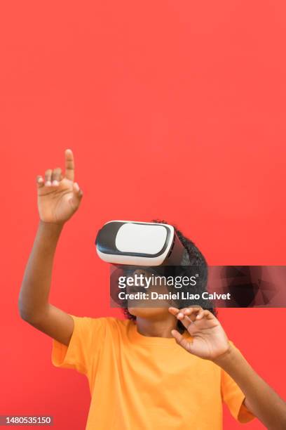 boy using virtual reality simulator gesturing against red background - fondo rojo stock pictures, royalty-free photos & images