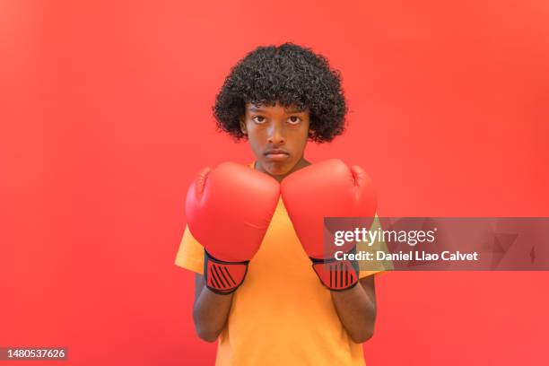 boy covering part of his face with red boxing gloves - fondo rojo stock pictures, royalty-free photos & images