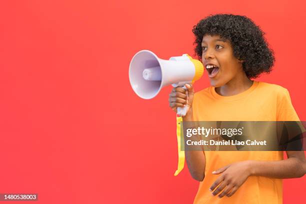 an african american boy yells into a megaphone in the studio - fondo rojo stock pictures, royalty-free photos & images