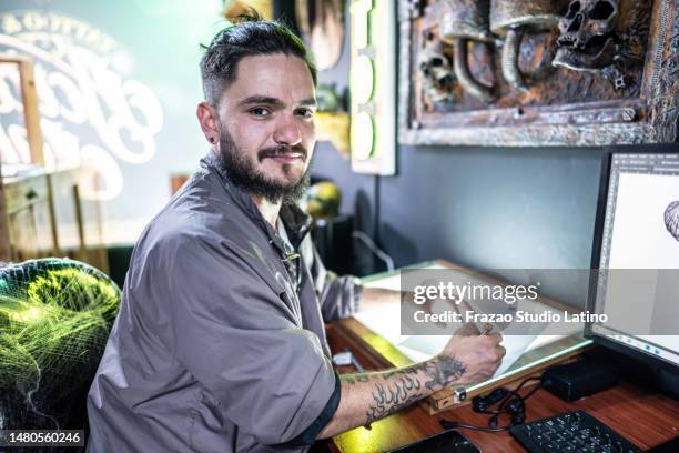 portrait of a young man drawing on a paper at tattoo studio - alternative lifestyle stock pictures, royalty-free photos & images