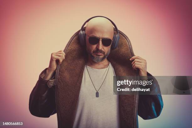 excéntrico y carismático hombre calvo con abrigo largo de piel y camiseta blanca sin mangas con auriculares y gafas de sol - showing off fotografías e imágenes de stock