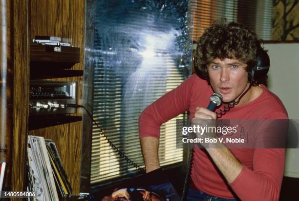 American actor and singer David Hasselhoff, wearing a red long-sleeve t-shirt as he holds a microphone which he sings into at his home in the...