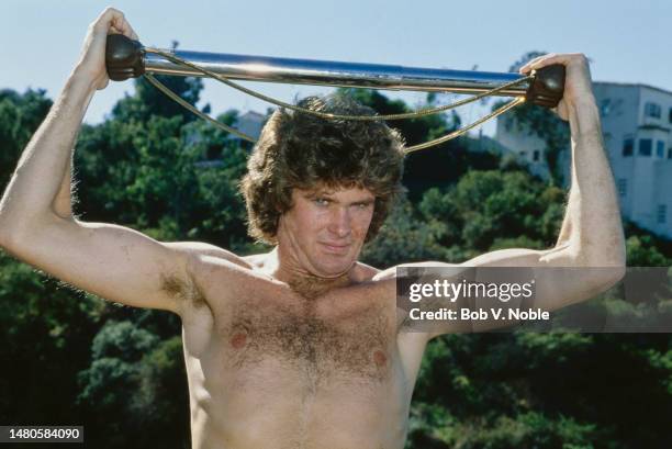 American actor and singer David Hasselhoff, barechested with a piece of exercise equipment held above his head, at his home in the Hollywood Hills...