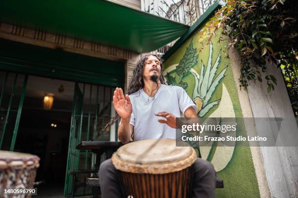 uomo maturo che suona il tamburo djembe all'aperto - djembe foto e immagini stock