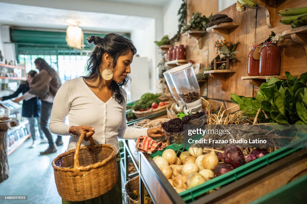 Mid adult woman buying vegetables at small local store