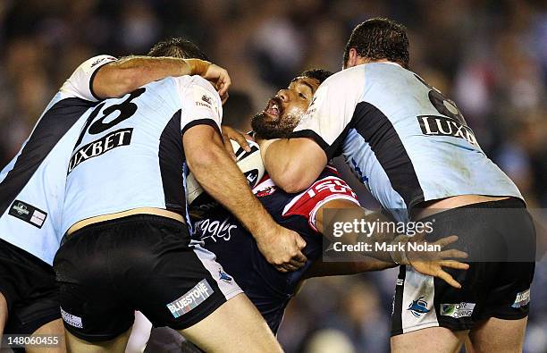 Mose Masoe of the Roosters is tackled during the round 18 NRL match between the Cronulla Sharks and the Sydney Roosters at Toyota Stadium on July 9,...