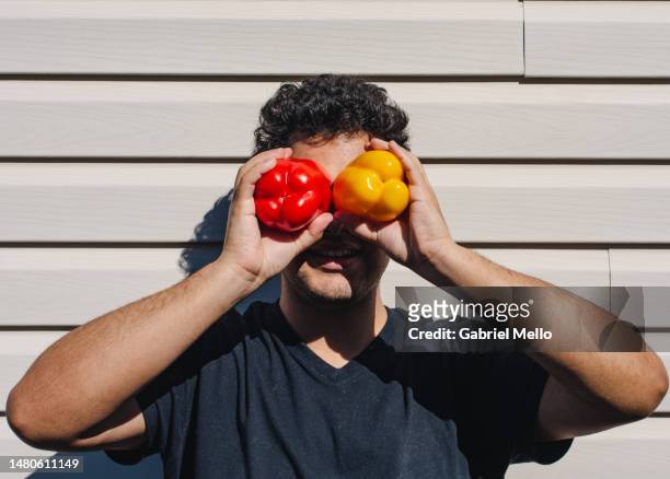 portrait of man holding a red and a yellow pepper - paprika stock pictures, royalty-free photos & images