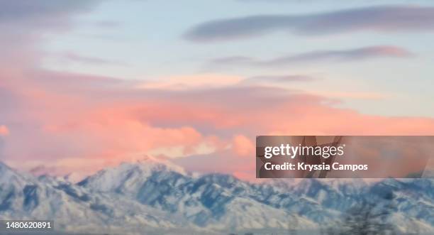 defocused view pink clouds posing above snowcapped mountains at sunset for backgrounds - wasatch-mountains stockfoto's en -beelden
