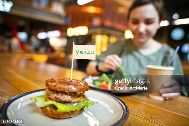 woman eating veggie burger in a vegan cafe or restaurant or food court - burger with flag stock pictures, royalty-free photos & images