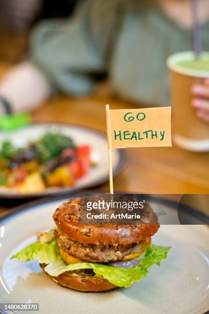 woman eating veggie burger in a vegan cafe or restaurant - burger with flag stock pictures, royalty-free photos & images