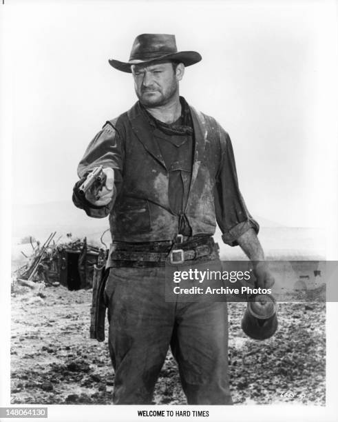 Aldo Ray wearing western attire pointing a gun in a scene from the film 'Welcome To Hard Times', 1967.