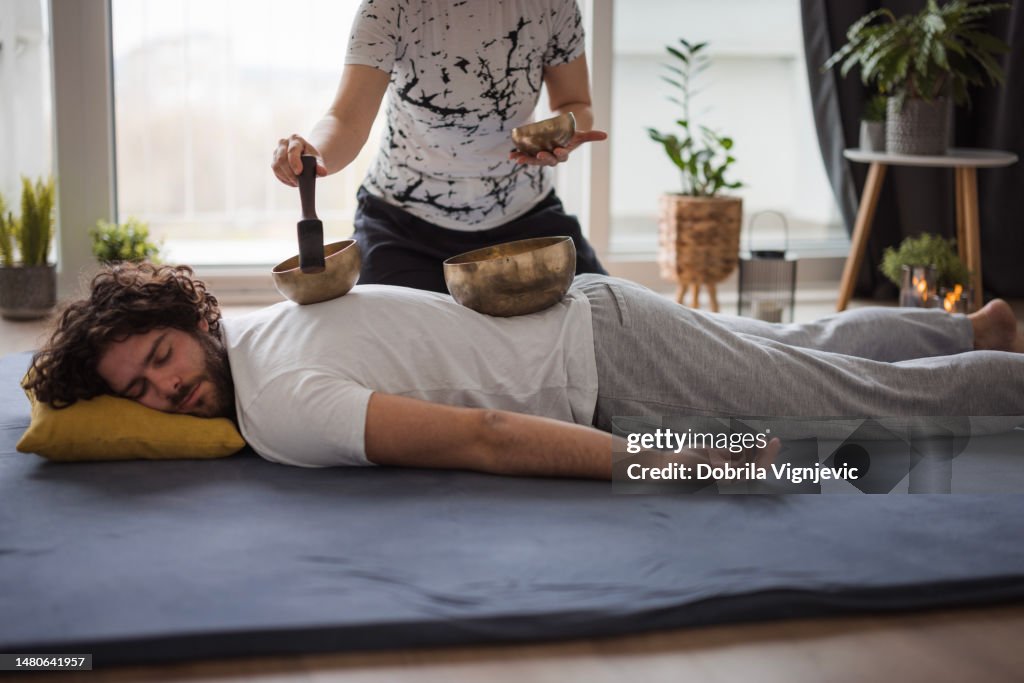 Hombre deshaciéndose del dolor de espalda con masaje tibetano con cuenco cantor