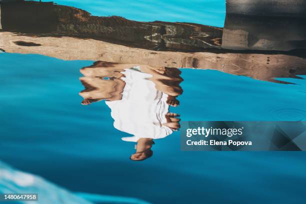 reflection view adult female yoga instructor practicing at the riverside on sunny summer morning - reflexo imagens e fotografias de stock