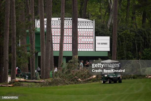 Signage that reads 'Play Suspended' on the leaderboard as fallen trees are seen on the 17th hole during the second round of the 2023 Masters...